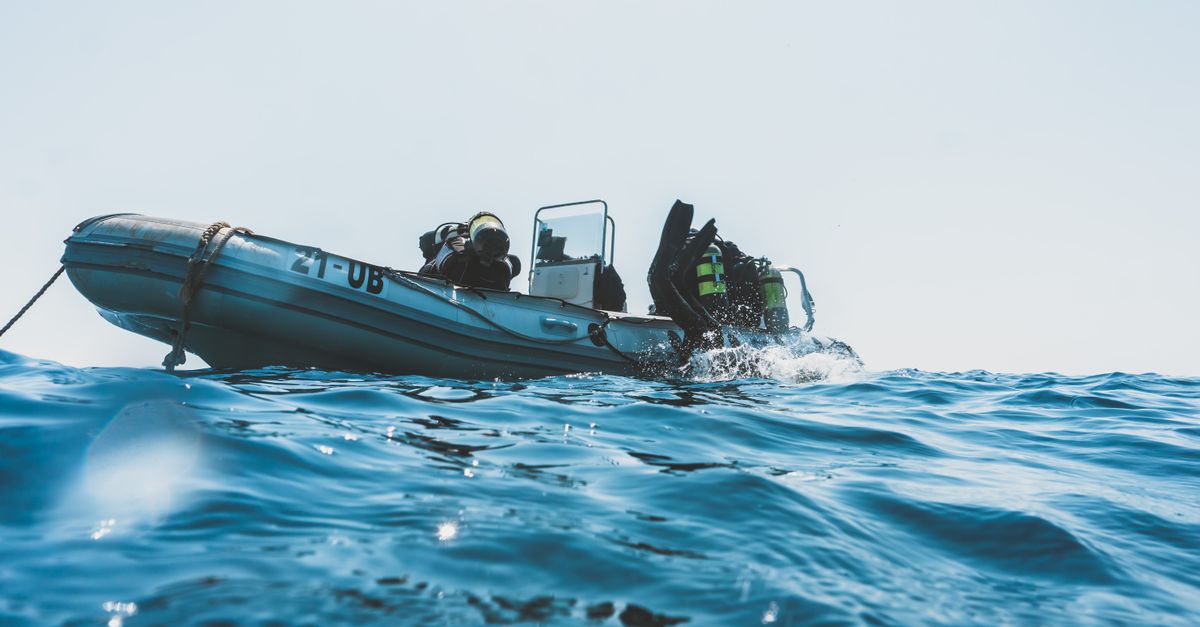 Divers preparing gear on a liveaboard deck before checking the dive plan.