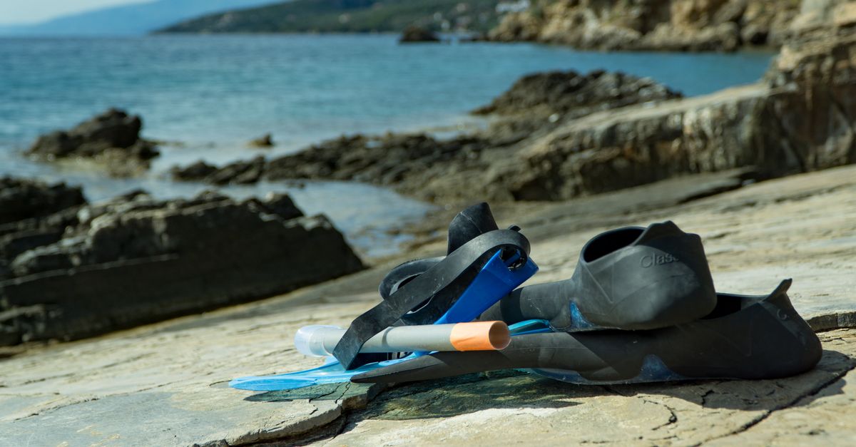 Dive gear arranged for packing beside a checklist and a travel bag.
