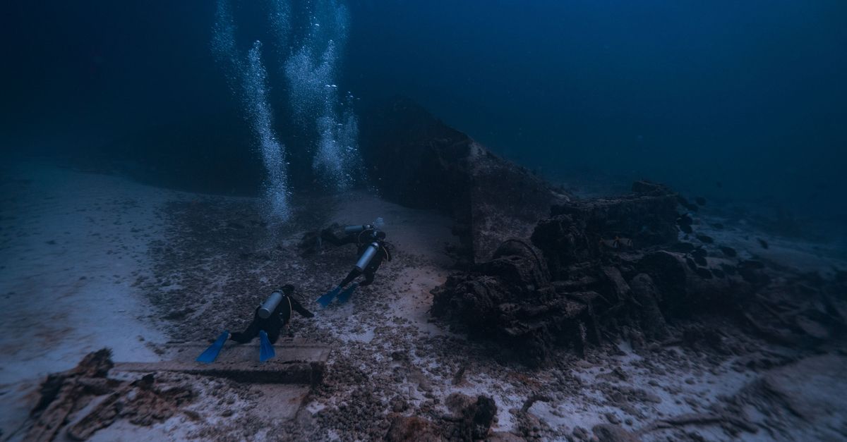 Large scuttled shipwreck structure rising from the sandy seabed on a Malta wreck dive.