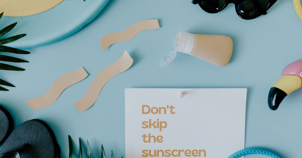 Reef-safe sunscreen bottles and a rashguard laid out on a wooden poolside table.